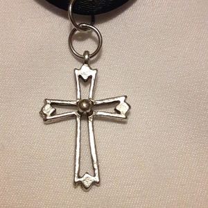 Silver cross charm on black necklace
